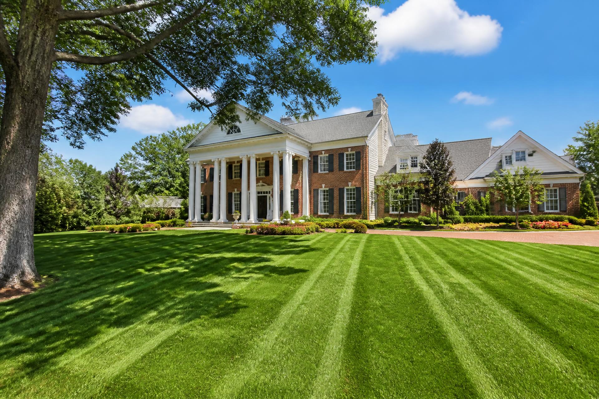 Large traditional brick home in Tyler, Texas with a freshly installed, brightly striped green lawn in daylight
